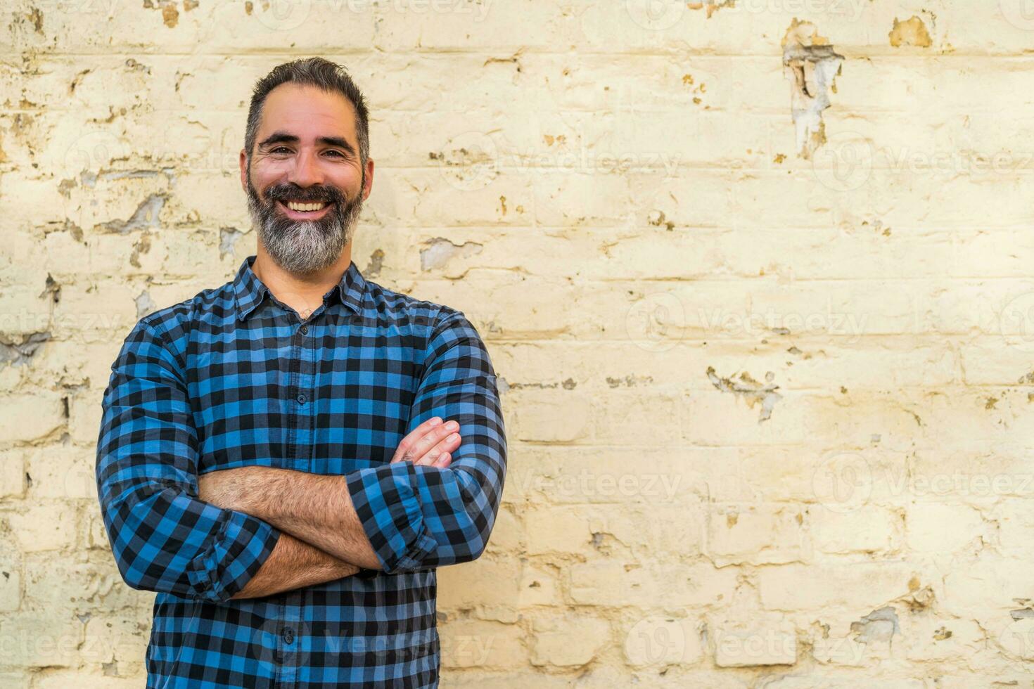 Portrait of modern businessman with beard standing in front of brick wall outdoor photo