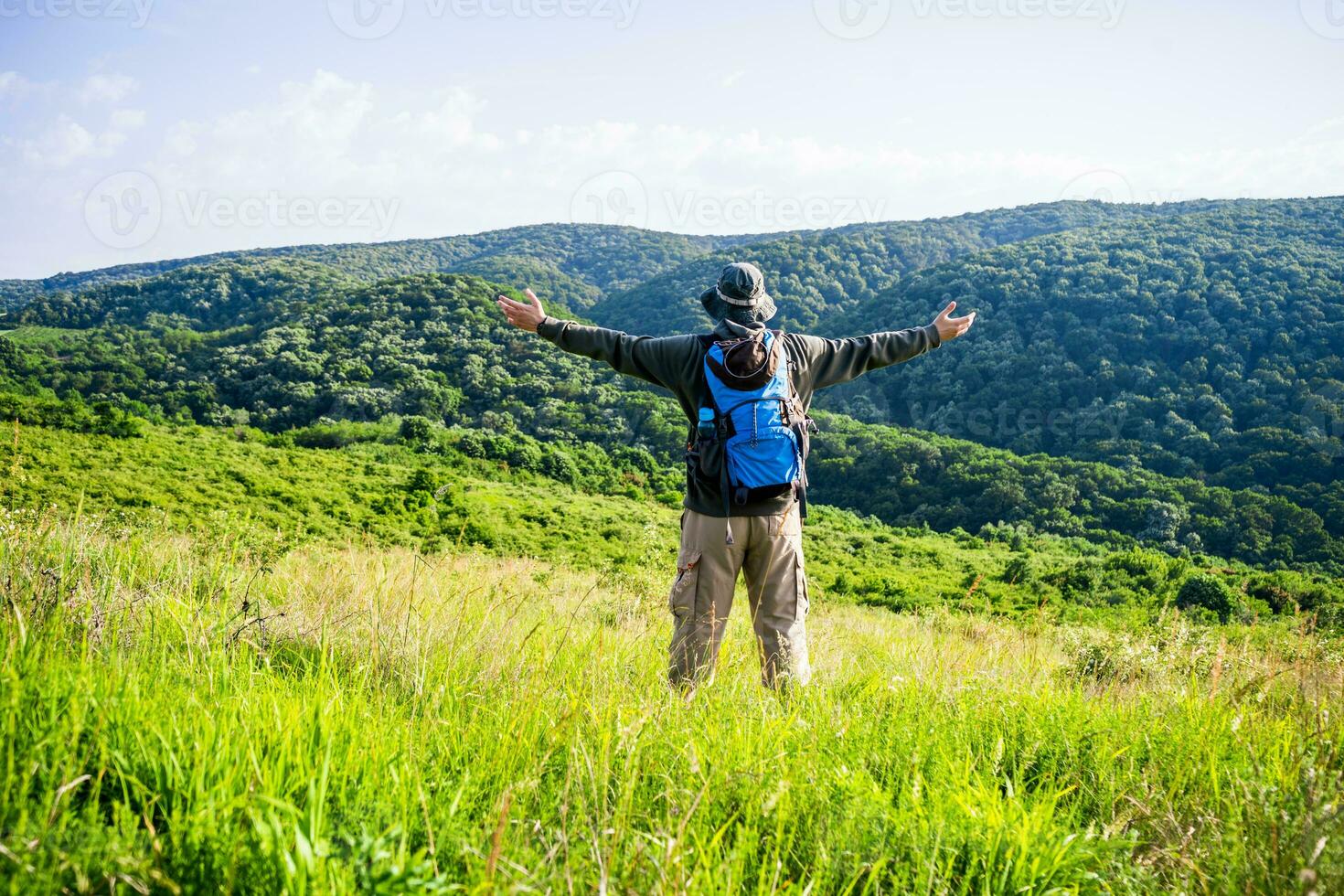 Man hiker with arms raised enjoys in beautiful view in the nature photo