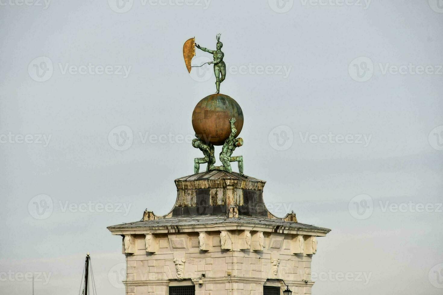 a statue of people holding a large ball on top of a tower photo