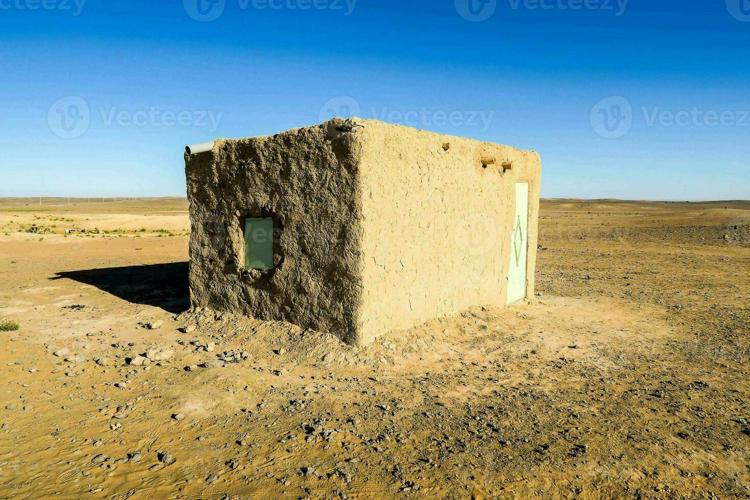 a small building in the desert with a blue sky photo