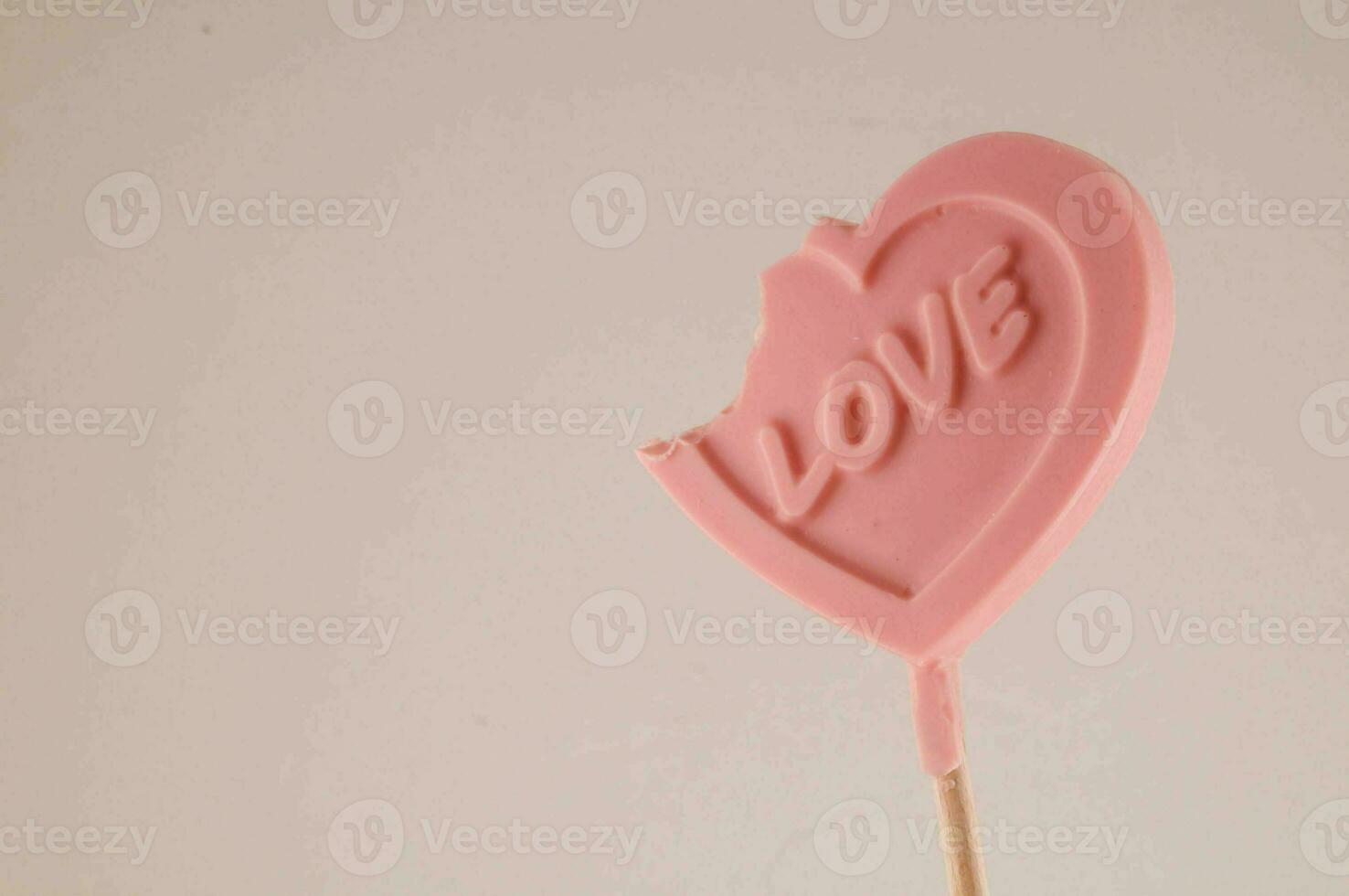 a pink heart shaped lollipop with a bite out of it photo