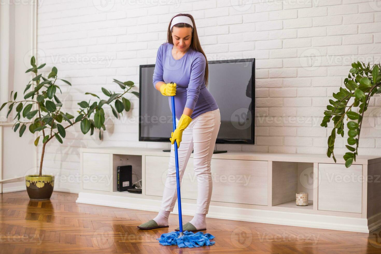 Beautiful pregnant woman enjoys cleaning her house. photo