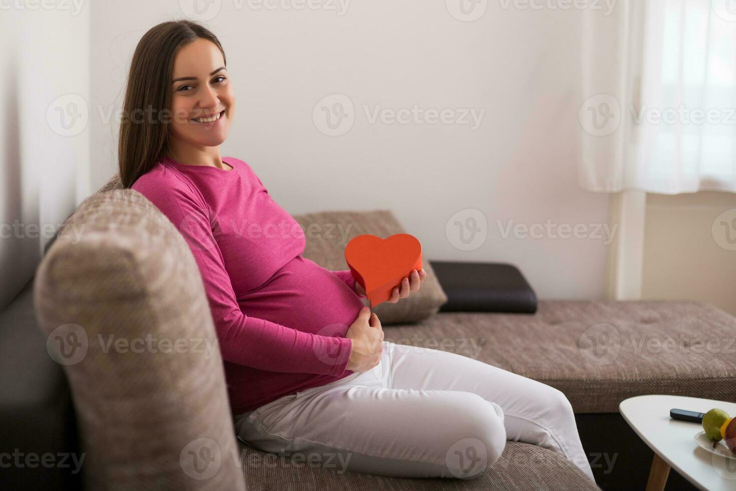 Happy pregnant woman pregnant  holding red heart shape. photo