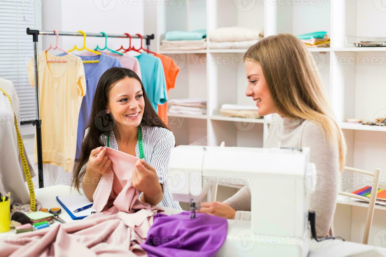 Seamstress is having meeting with her customer at workshop. photo