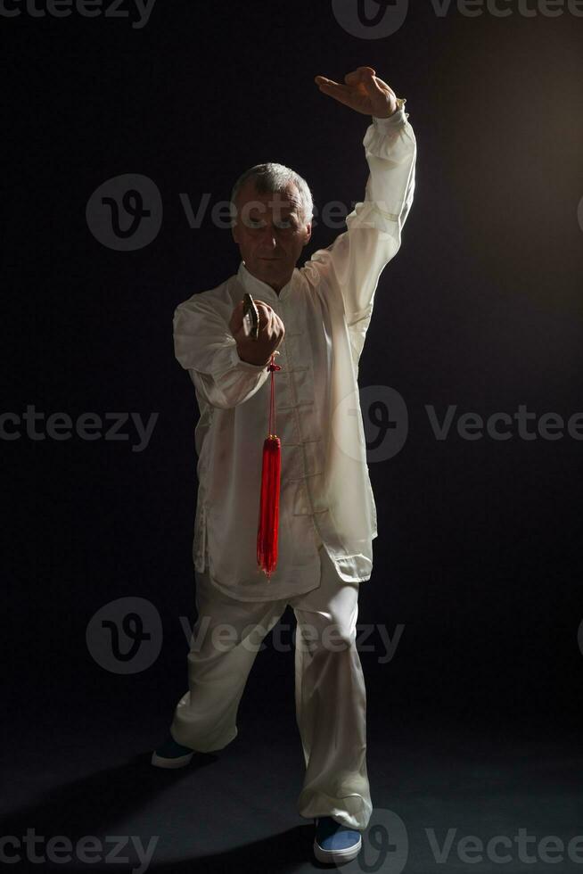 Senior man practicing Tai Chi with sword photo