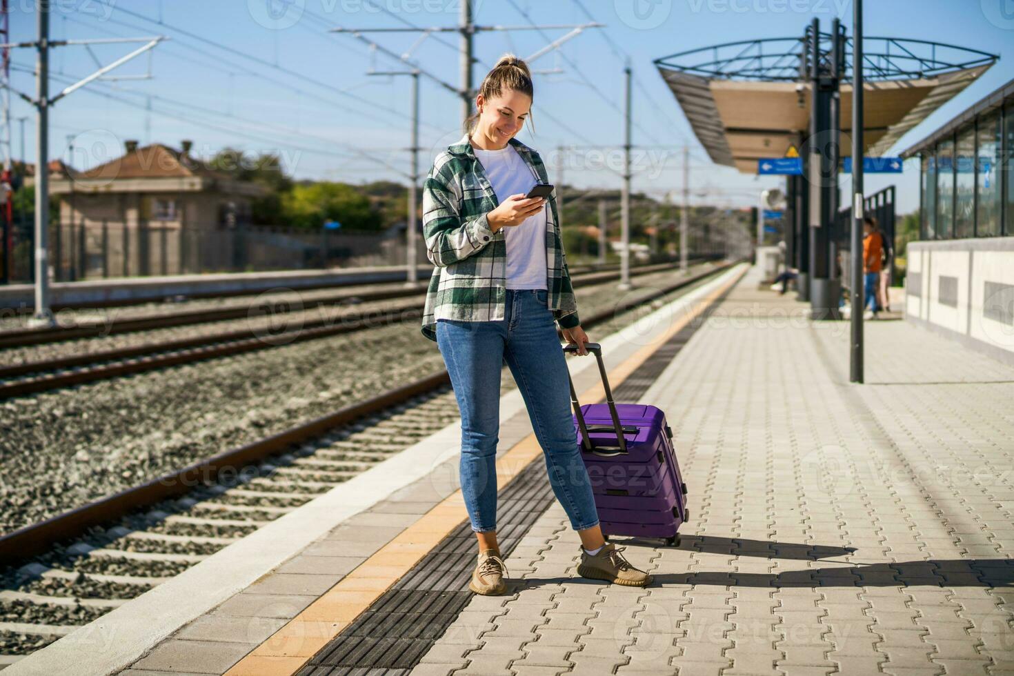 contento mujer utilizando móvil teléfono en un tren estación foto