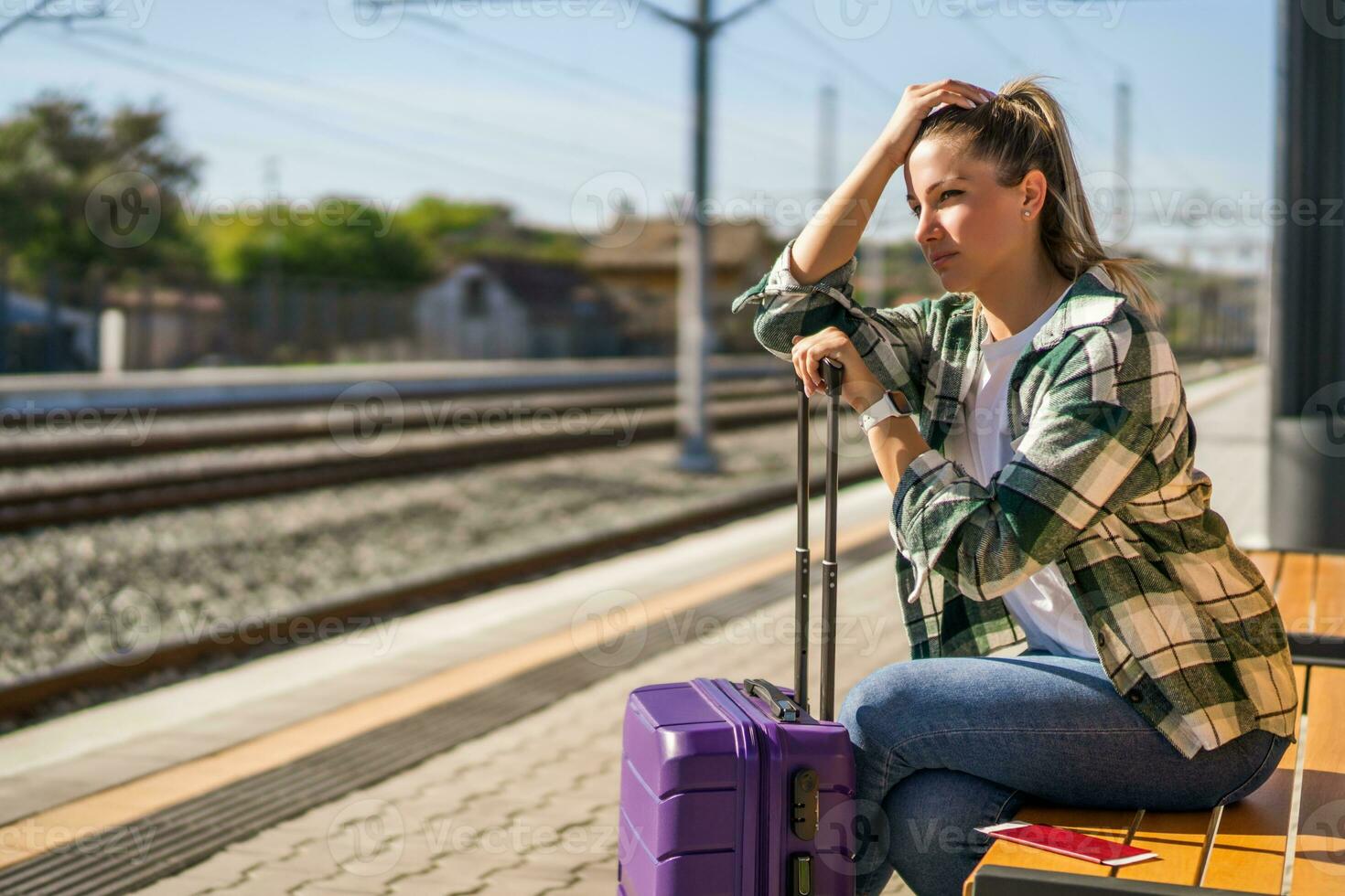 Worried woman sitting on a bench at the  train station photo