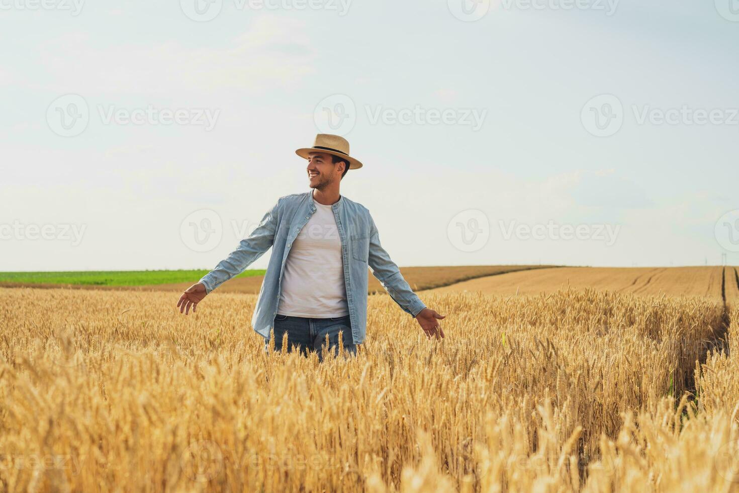 Happy farmer is standing in his growing wheat field photo