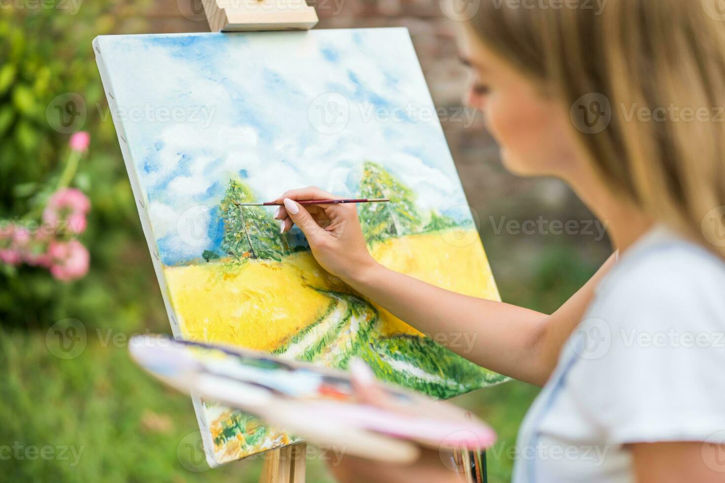 Woman enjoys woman painting on canvas outdoor photo