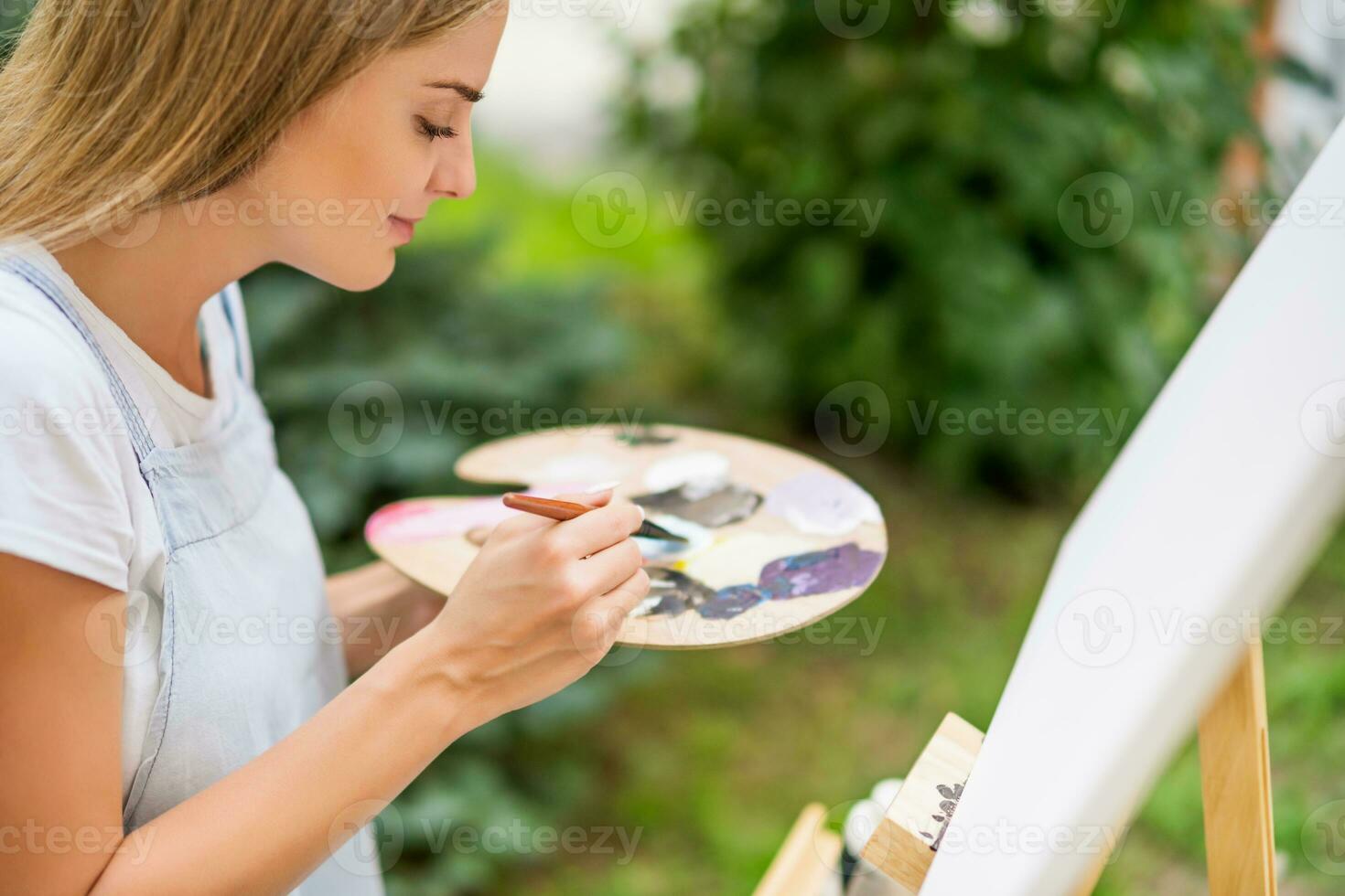 Woman enjoys woman painting on canvas outdoor. photo