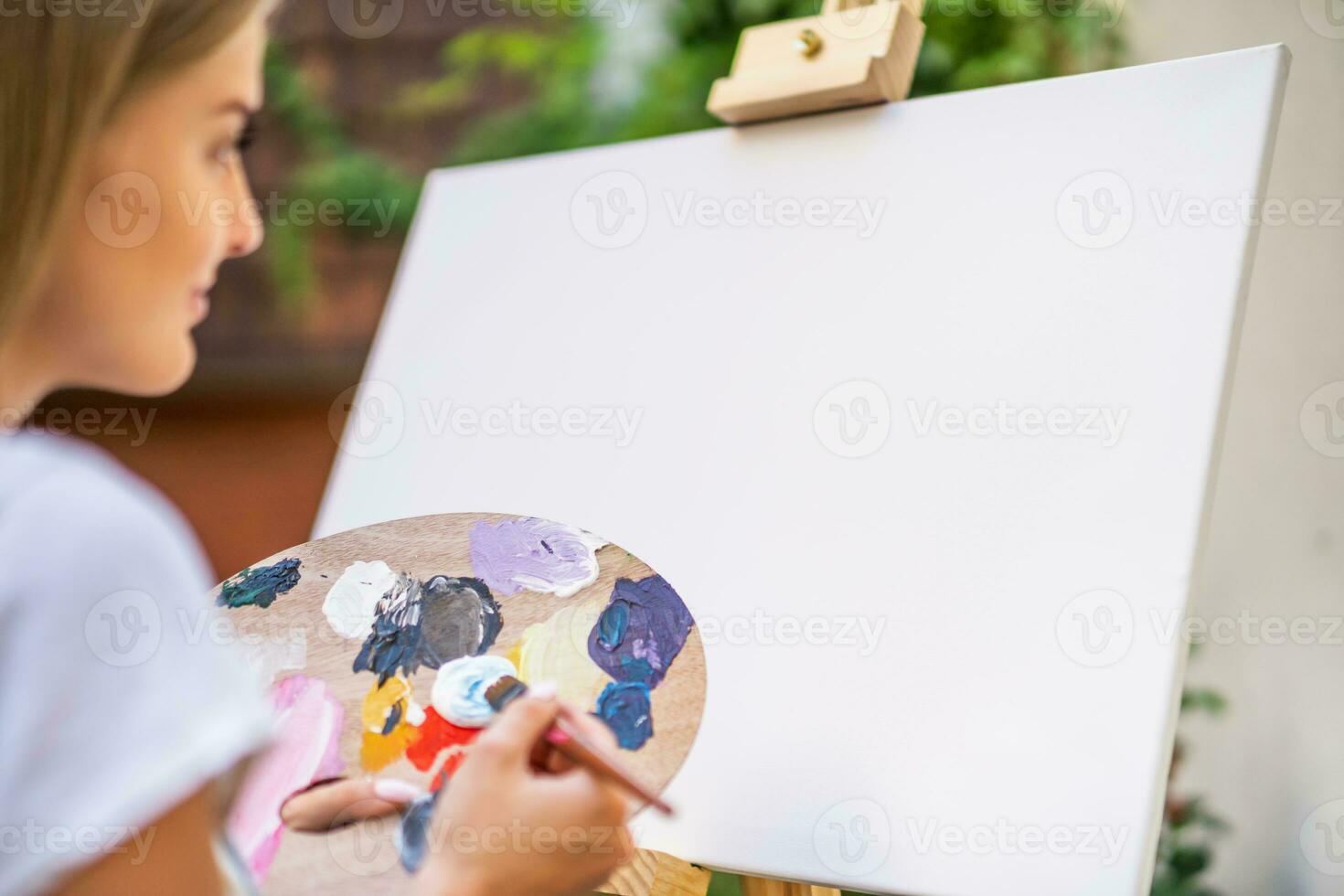 Woman enjoys woman painting on canvas outdoor. photo