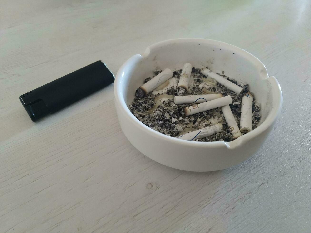 Cigarette butts in ashtray on wooden table. photo