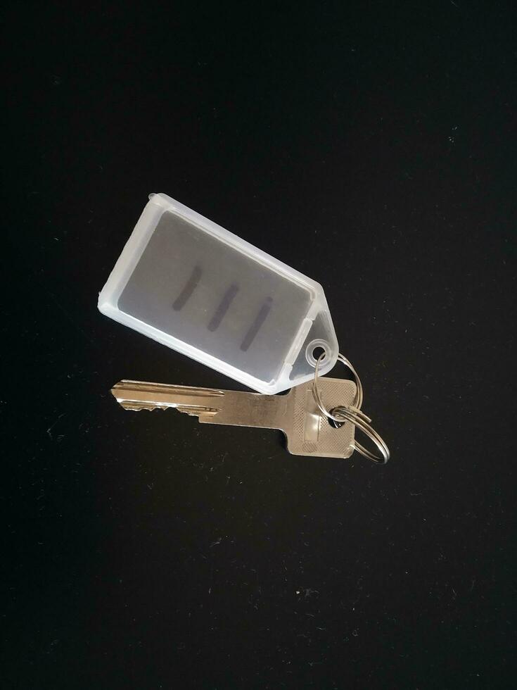 Key with a blank keychain on a black background, closeup of photo