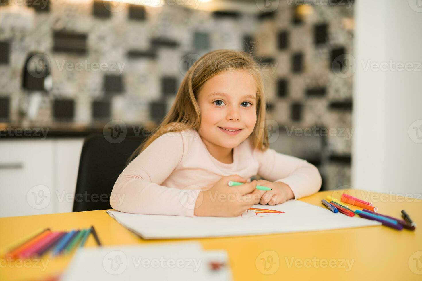 Beautiful little girl enjoys drawing at her home photo