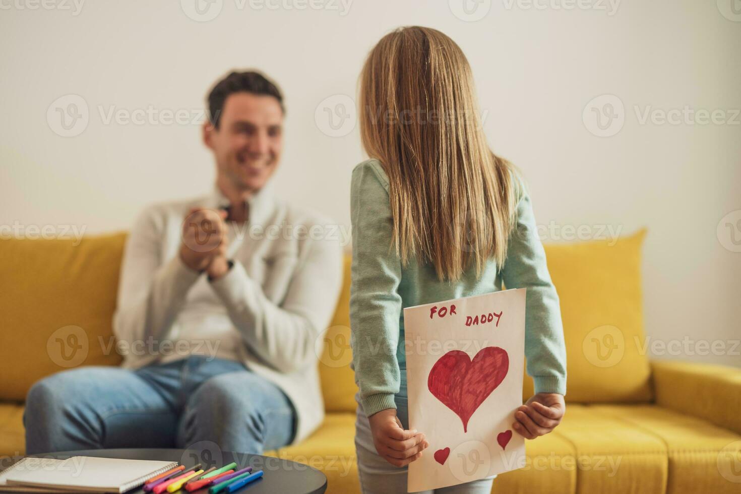 Happy  daughter holding greeting card with heart shapes and text for her father photo