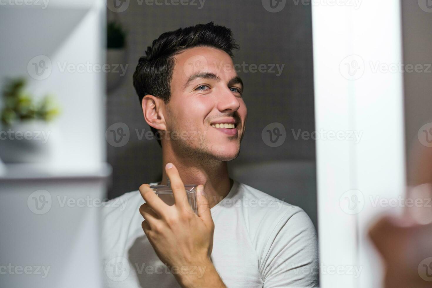 Man using perfume while looking himself in the mirror photo