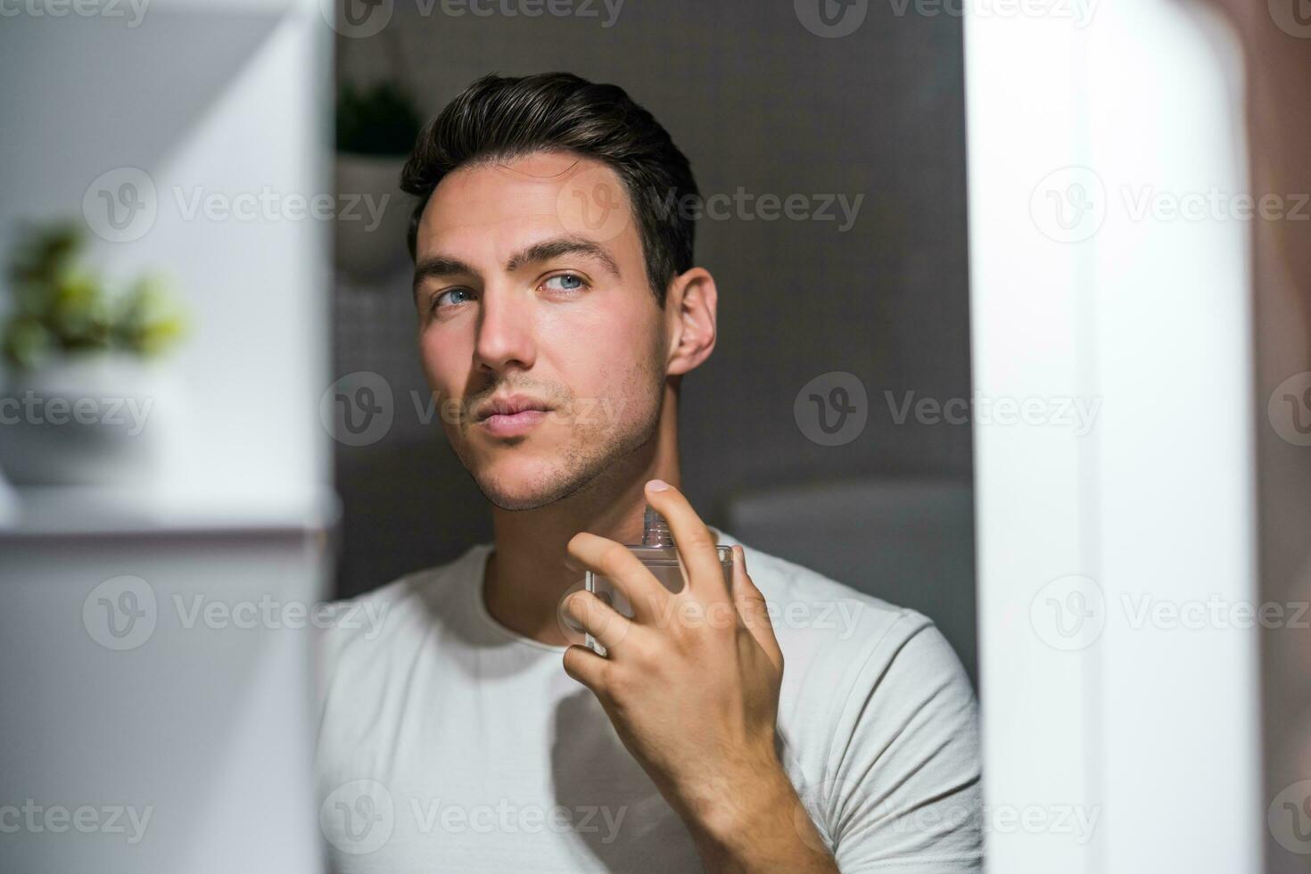 Man using perfume while looking himself in the mirror photo