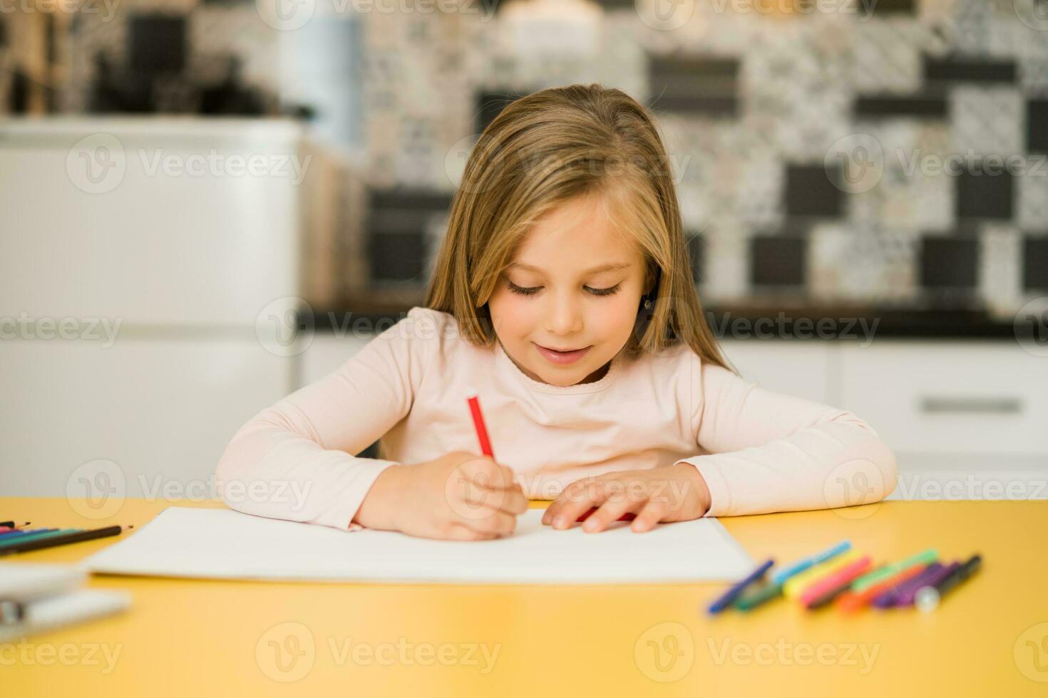 Beautiful little girl enjoys drawing at her home photo