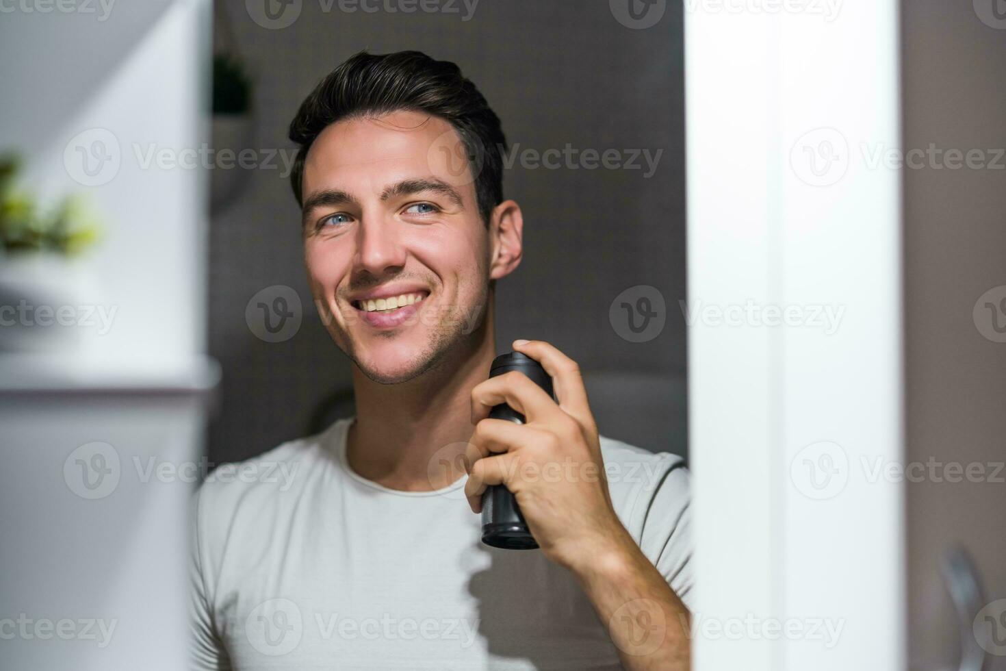 Man using deodorant while looking himself in the mirror photo