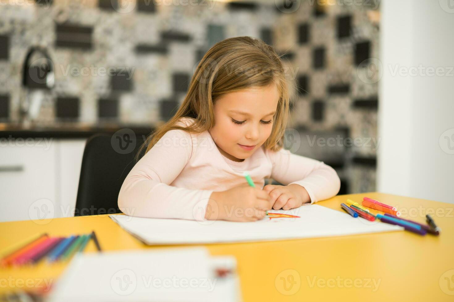 Beautiful little girl enjoys drawing at her home photo
