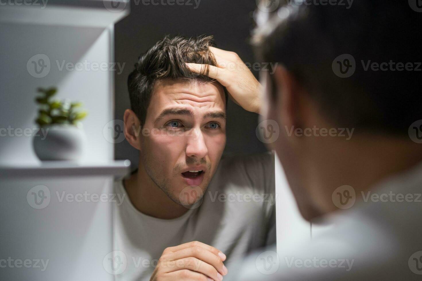 Worried man is looking his hair in the mirror photo