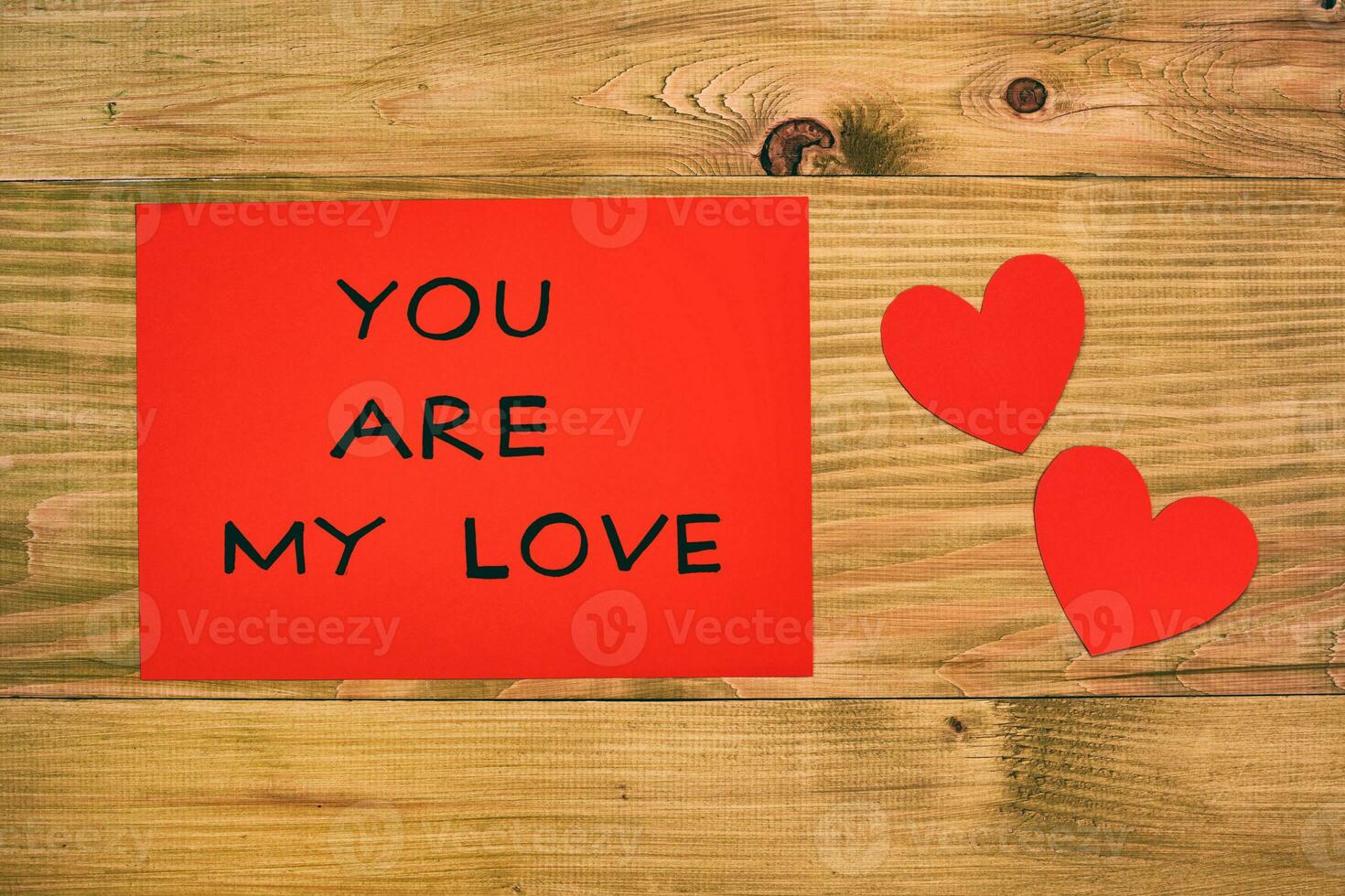 Message you are my love on red paper and hearts on wooden table photo