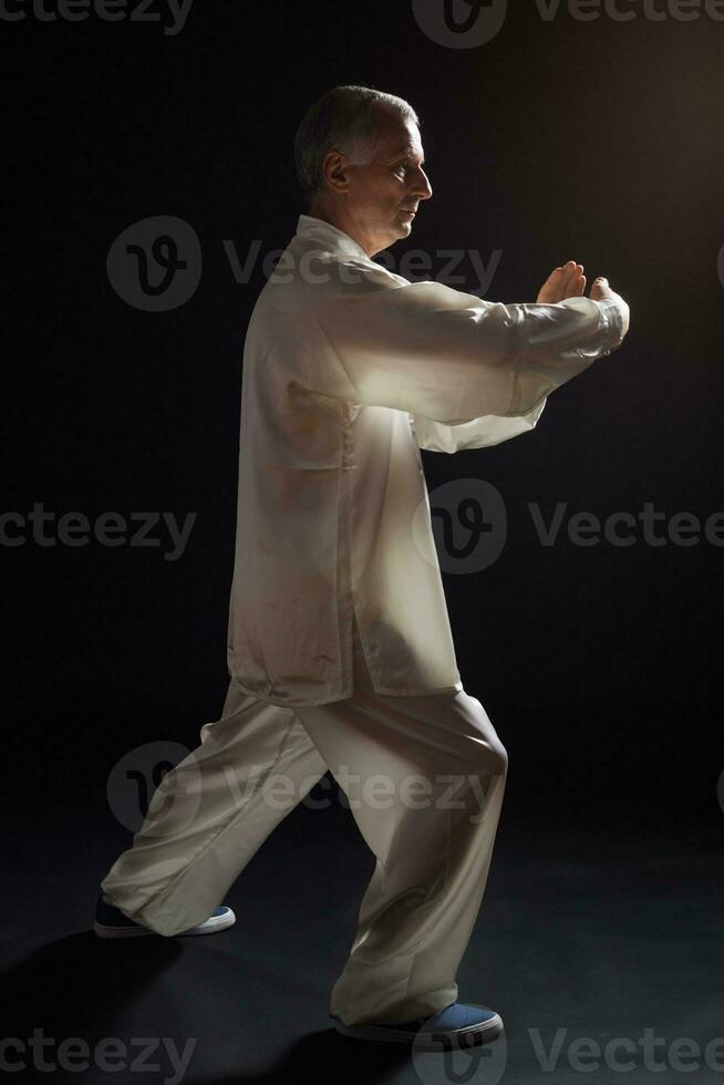 Senior man enjoys exercise Tai Chi indoor photo