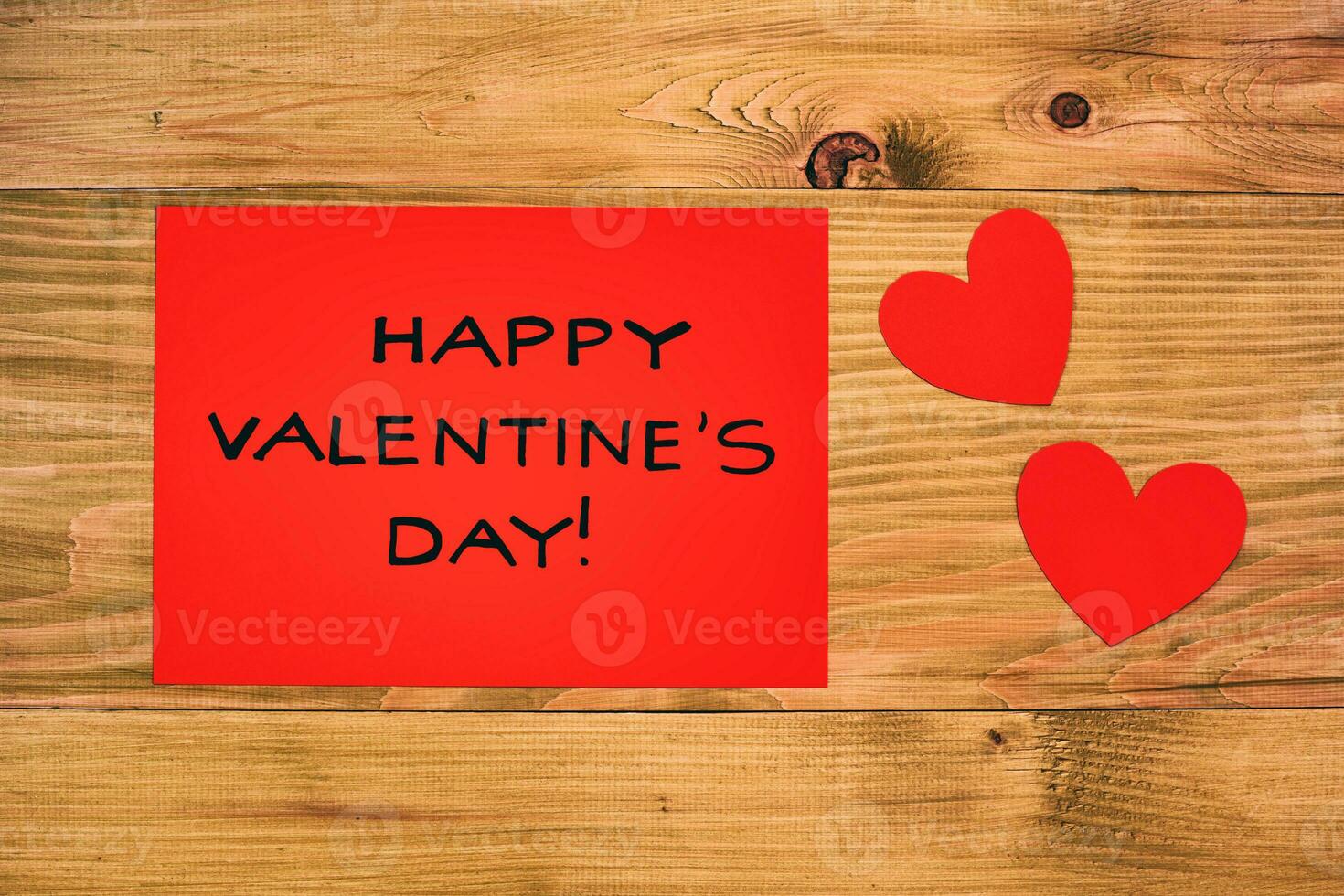 Red paper with message for Valentine's day and hearts on wooden table photo