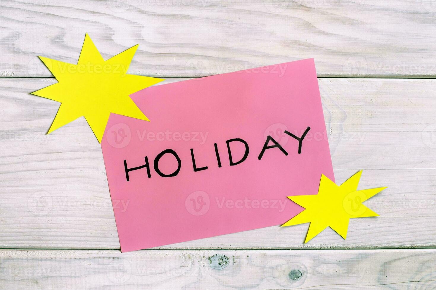Holiday text on a pink sticky note on a wooden table photo