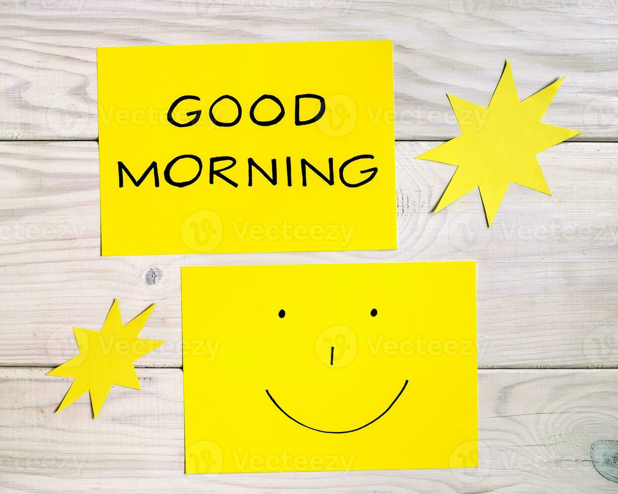 Text good morning and smiley face with sun shapes on wooden table photo