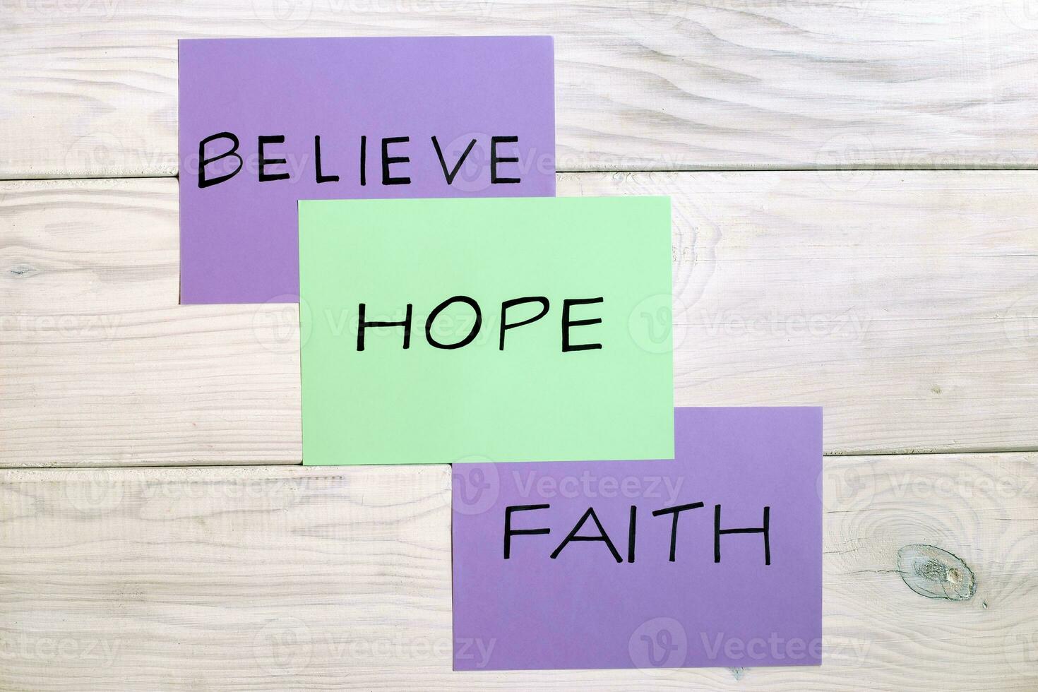 Three different colored post-it notes with the words believe, hope, and faith photo