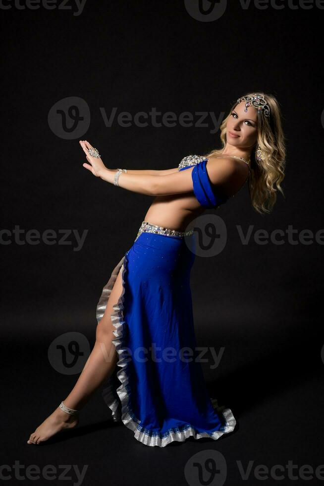 Beautiful belly dancer performing belly dance on black background photo