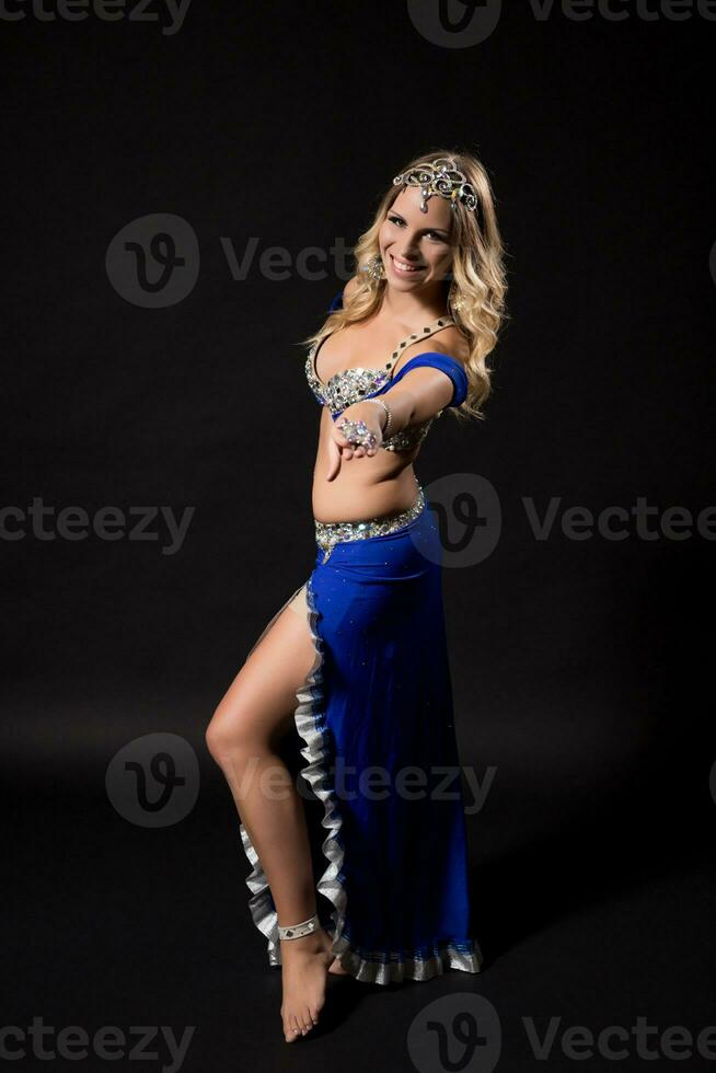 Beautiful belly dancer performing belly dance on black background photo