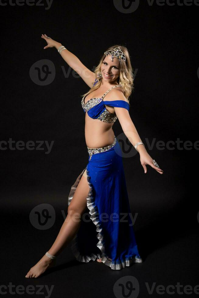 Beautiful belly dancer performing belly dance on black background photo