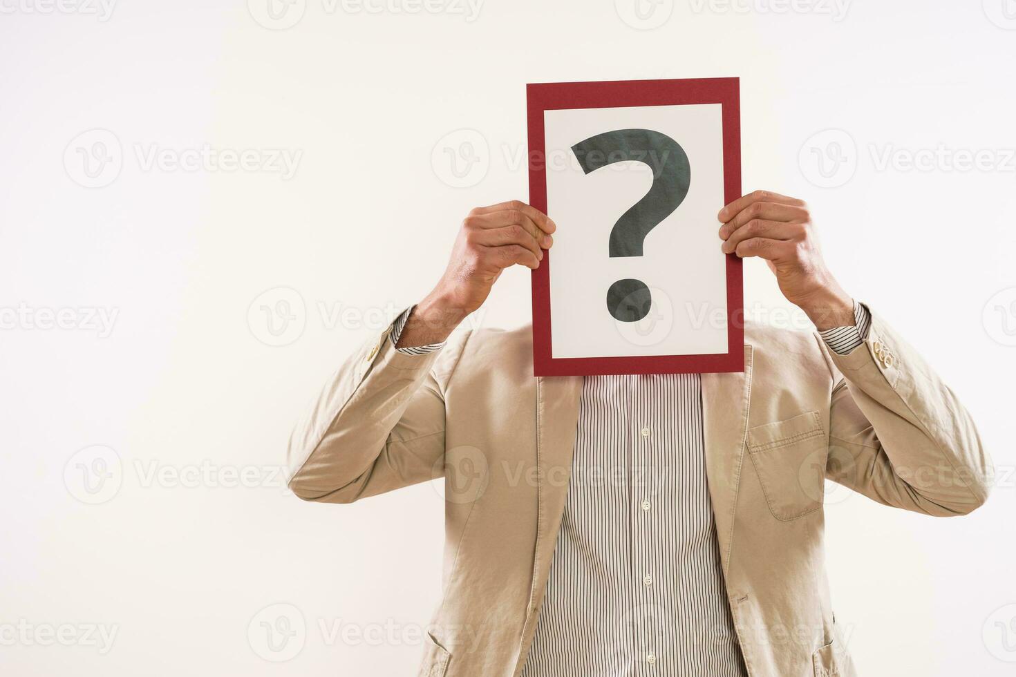 Confused businessman holding paper with question mark photo