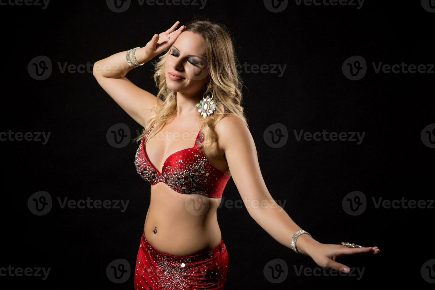 Beautiful belly dancer performing belly dance on black background photo