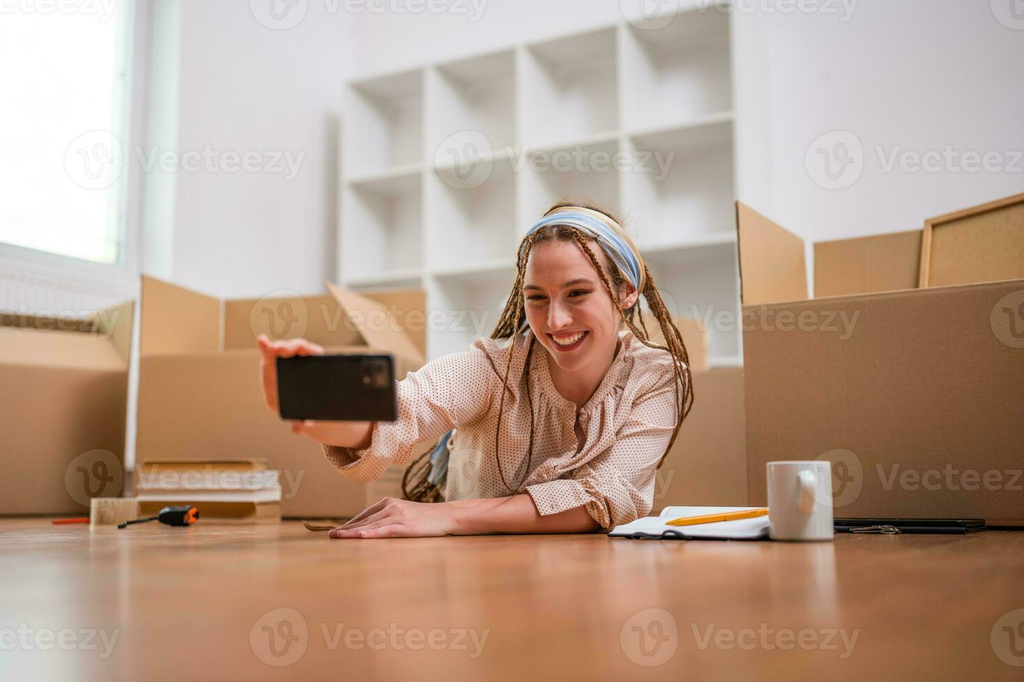 Excited ginger woman with braids taking selfie in her new home photo