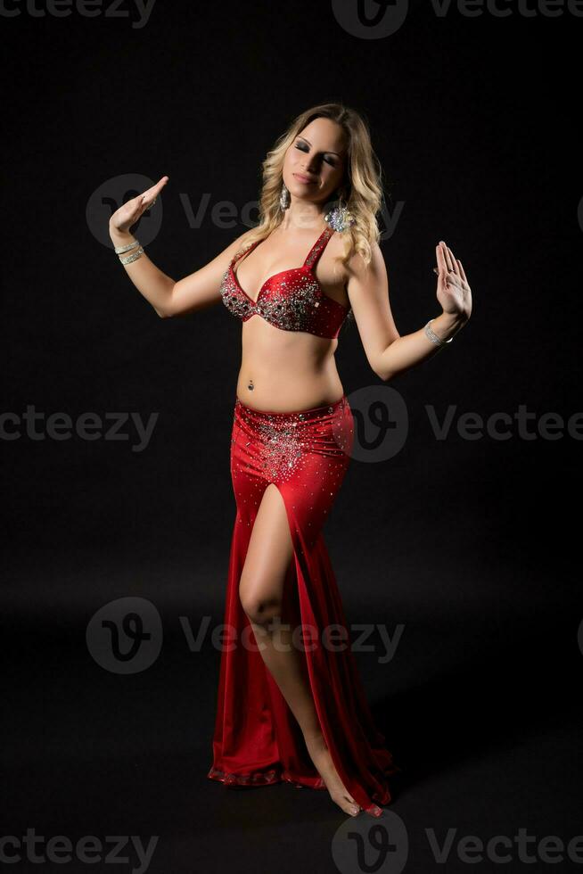 Beautiful belly dancer performing belly dance on black background photo
