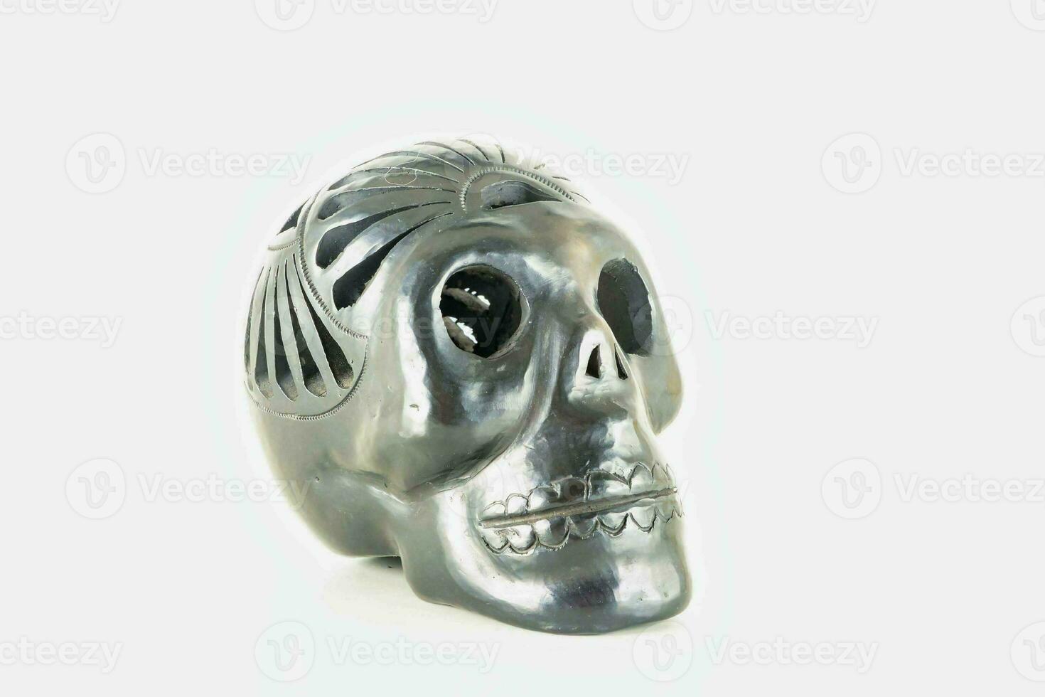 a silver skull figurine on a white surface photo