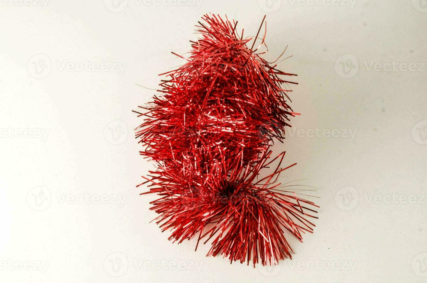 a red tinsel decoration on a white surface photo