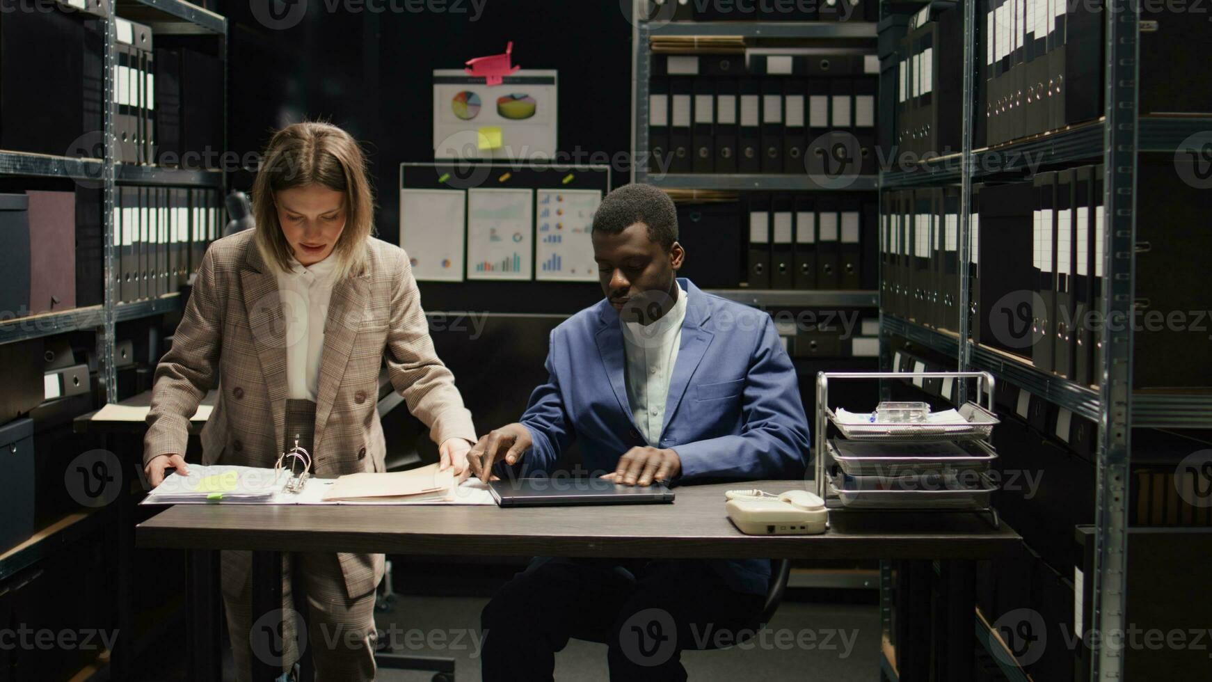 African american cop with bag enters evidence room with caucasian female detective. Two private investigators walk into the office, carrying case files and criminal records to be investigated. photo