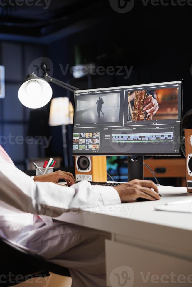 Detailed image of a creative male individual editing a movie on his desktop computer. Selective focus on the pc monitor displaying the work of a freelance videographer, filmmaker. photo