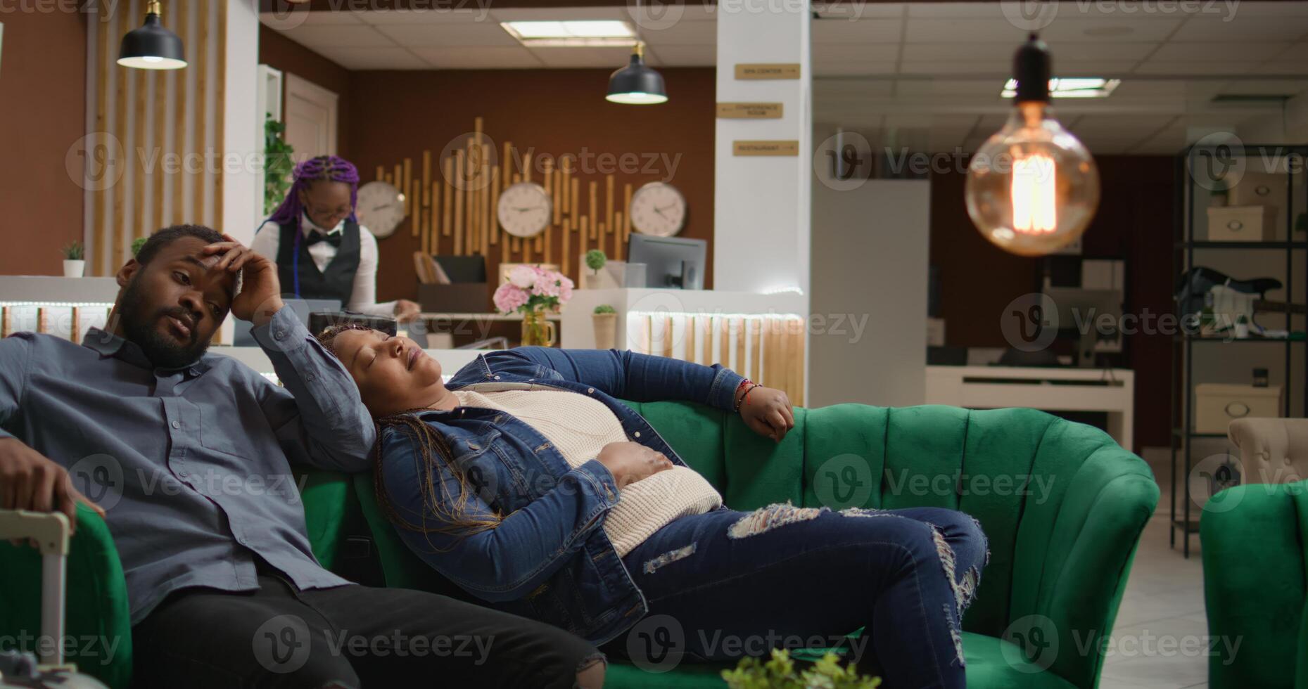 Symptoms of vacation jet lag. African american couple arriving at holiday destination and feeling sleepy in lobby, tarvellers resting on lounge area sofa in hotel reception, waiting for check in. photo