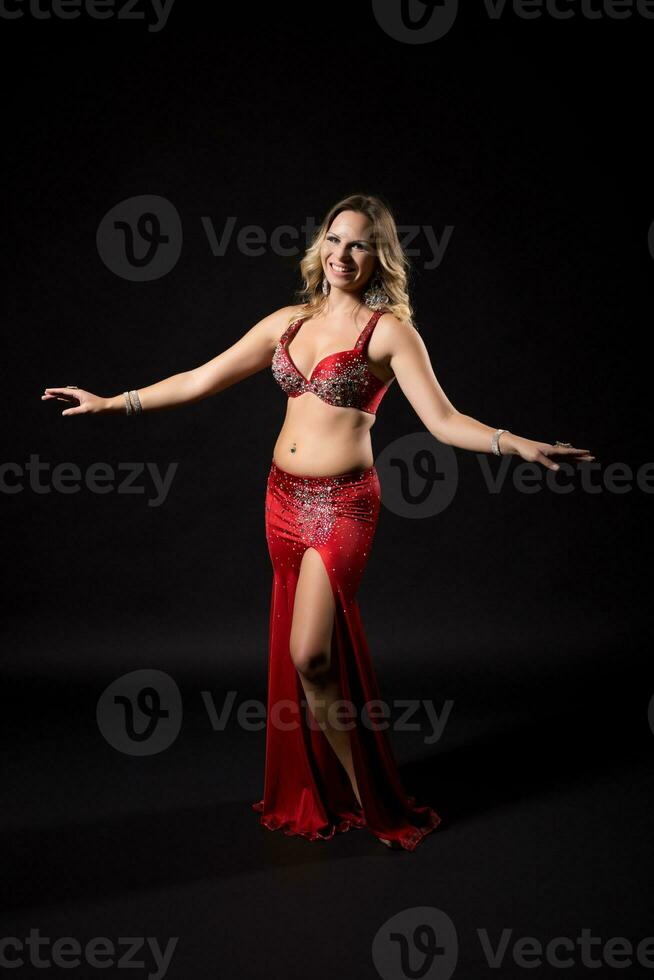 Beautiful belly dancer performing belly dance on black background photo