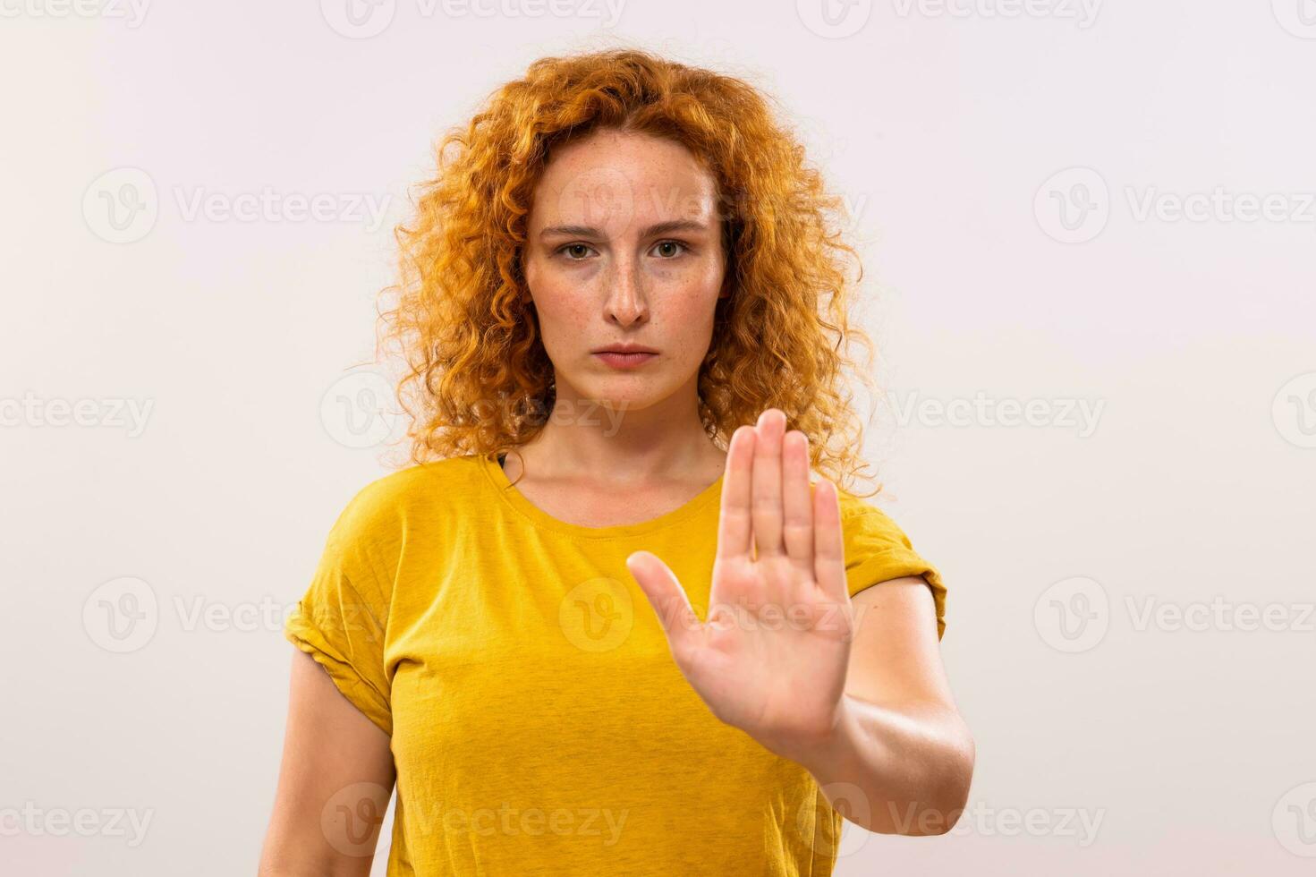 Image of serious ginger woman showing stop sign on gray background photo