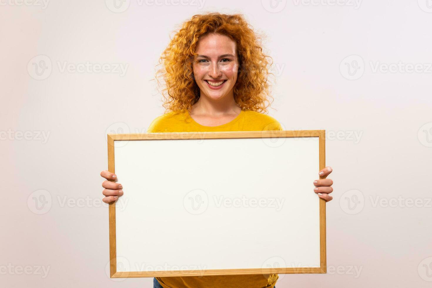 Beautiful ginger woman is holding white board photo