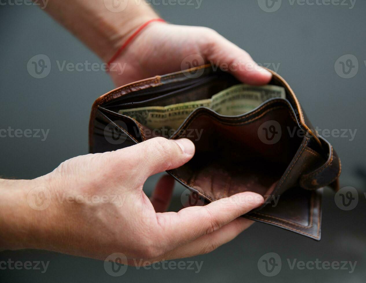 Male hands hold an open wallet and there is only one dollar in it. selective focus photo