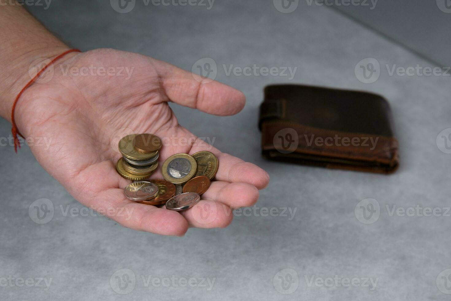 A man in his palm holds metal coins and a leather wallet lies nearby. selective focus photo