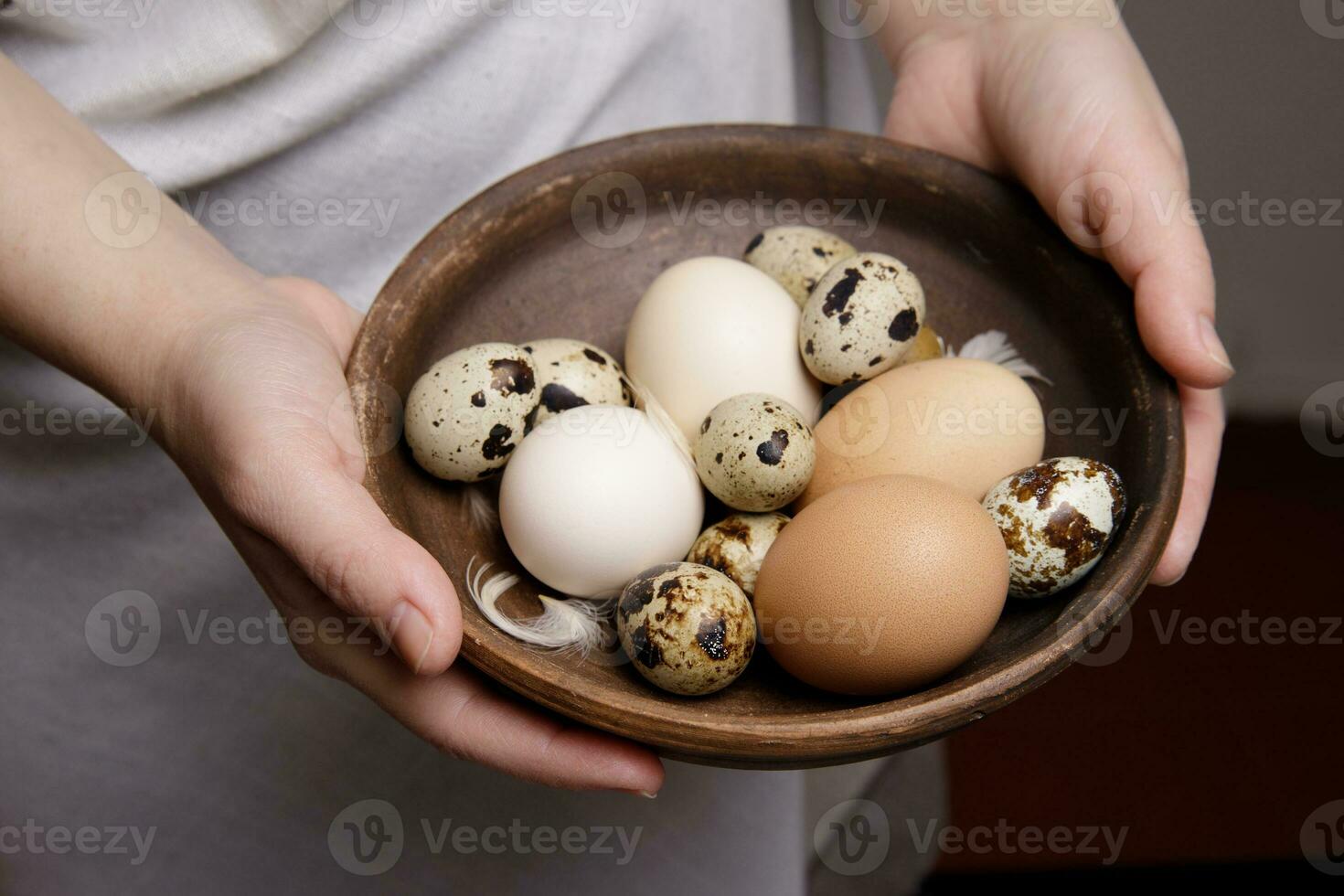 the hands of an invisible person hold fresh chicken and quail eggs from the farm in front of them in earthenware. photo
