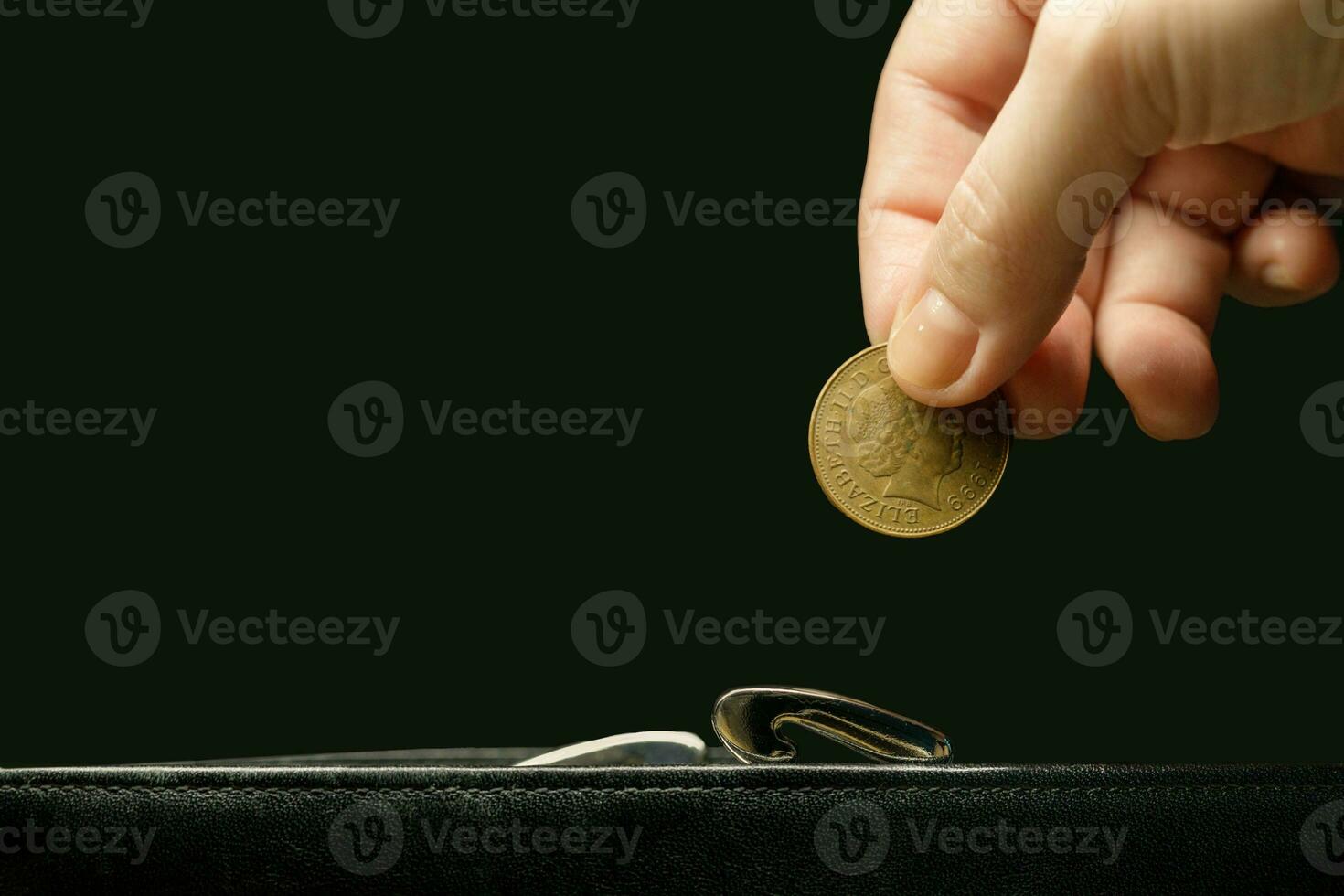 an invisible woman's hand puts a coin in a wallet.a black background photo